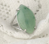 Silver ring with a green stone on a textured white background