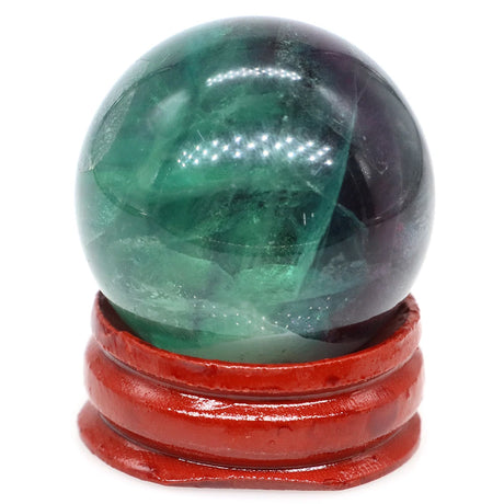 Green crystal ball on a red stand against a white background
