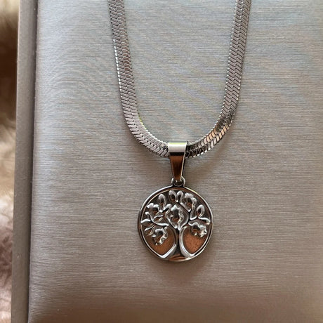 Silver necklace with a tree-of-life pendant on a textured surface