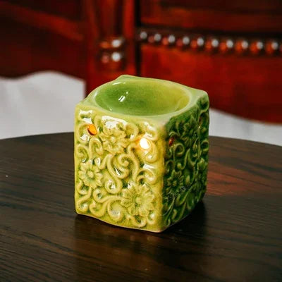 Decorative green candle holder on a wooden surface with a blurred background