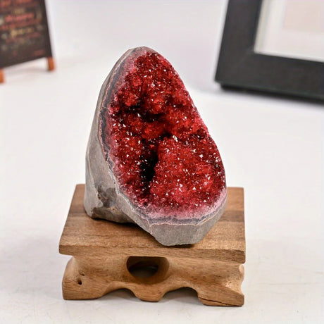 Red geode crystal on a wooden stand with a white background