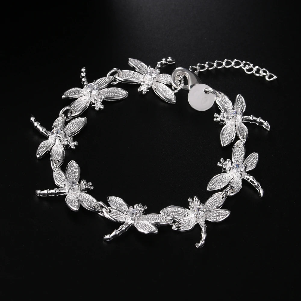 Silver bracelet with dragonfly designs on a black background