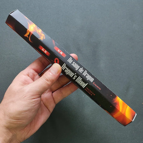 Hand holding a product with 'Dragon's Blood' branding against a dark background