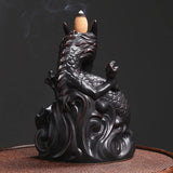 Black dragon-shaped incense burner with a burning incense stick on a dark background