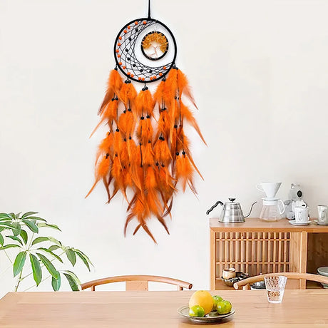 Orange feathered dreamcatcher hanging on a white wall above a wooden table with a plant and small items.