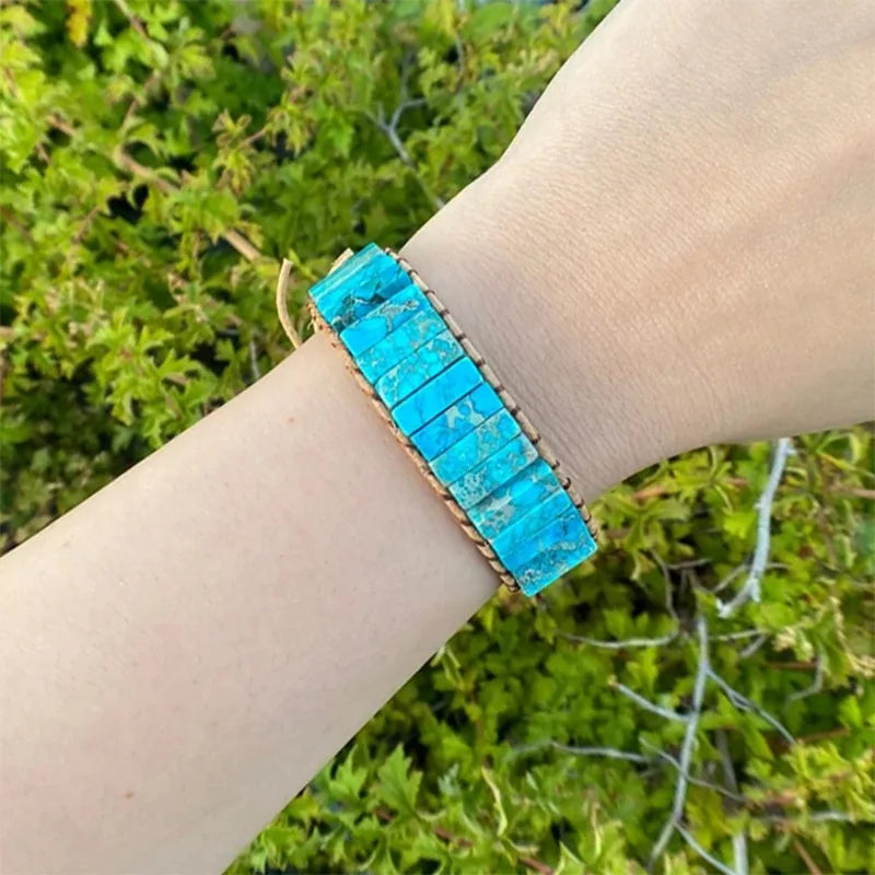 Turquoise bracelet on a wrist with a green leafy background