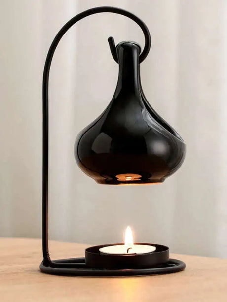 Black table lamp with a lit candle on a wooden surface