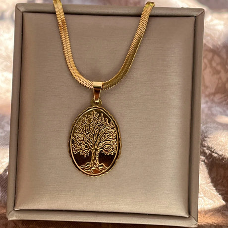 Gold necklace with a tree pendant on a beige box