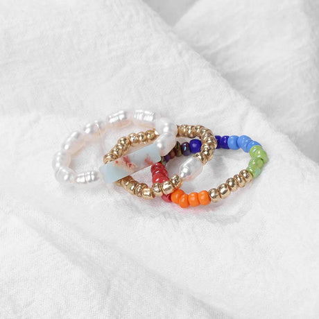 Set of colorful beaded rings on a white fabric background