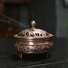 Bronze incense burner with intricate designs on a dark surface