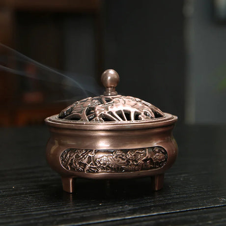 Bronze incense burner with intricate designs on a dark surface