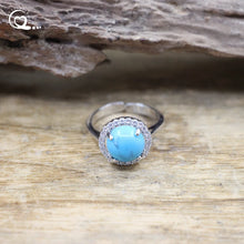 Silver ring with a turquoise stone on a wooden surface