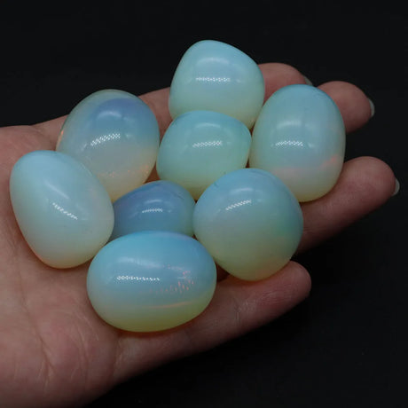 Hand holding a collection of blue and green ombre eggs against a dark background