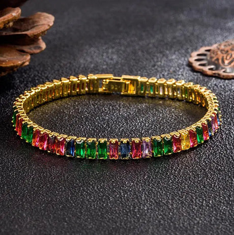 Gold bracelet with multicolored gemstones on a dark surface