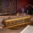 Decorative incense burner with smoking incense on a wooden surface.