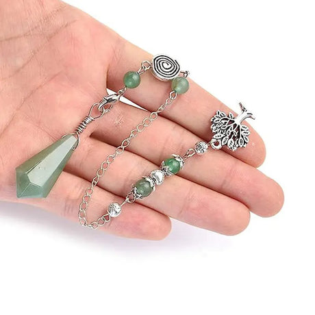 Hand holding a silver bracelet with green beads and a peacock feather charm on a white background