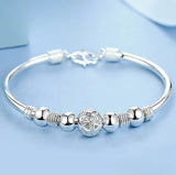 Silver bracelet with decorative beads on a light blue background