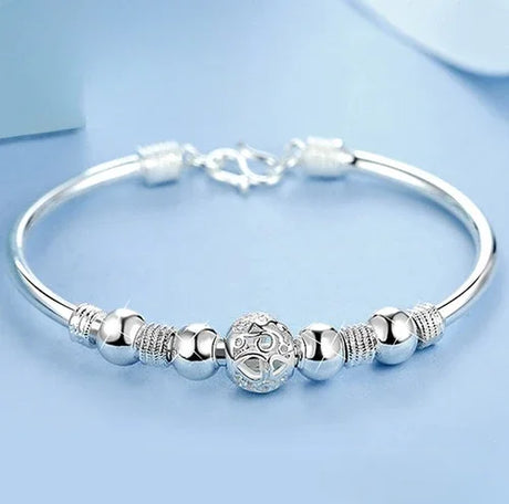 Silver bracelet with decorative beads on a light blue background