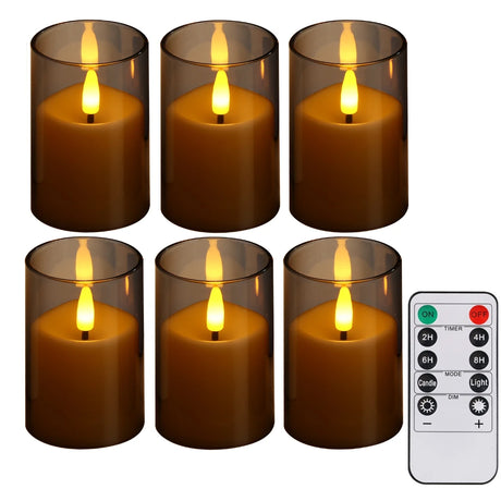 Set of six lit candles in clear holders with a remote control on a white background