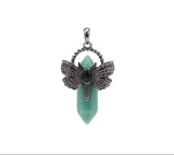 Jewelry pendant with butterfly design and green stone on a white background