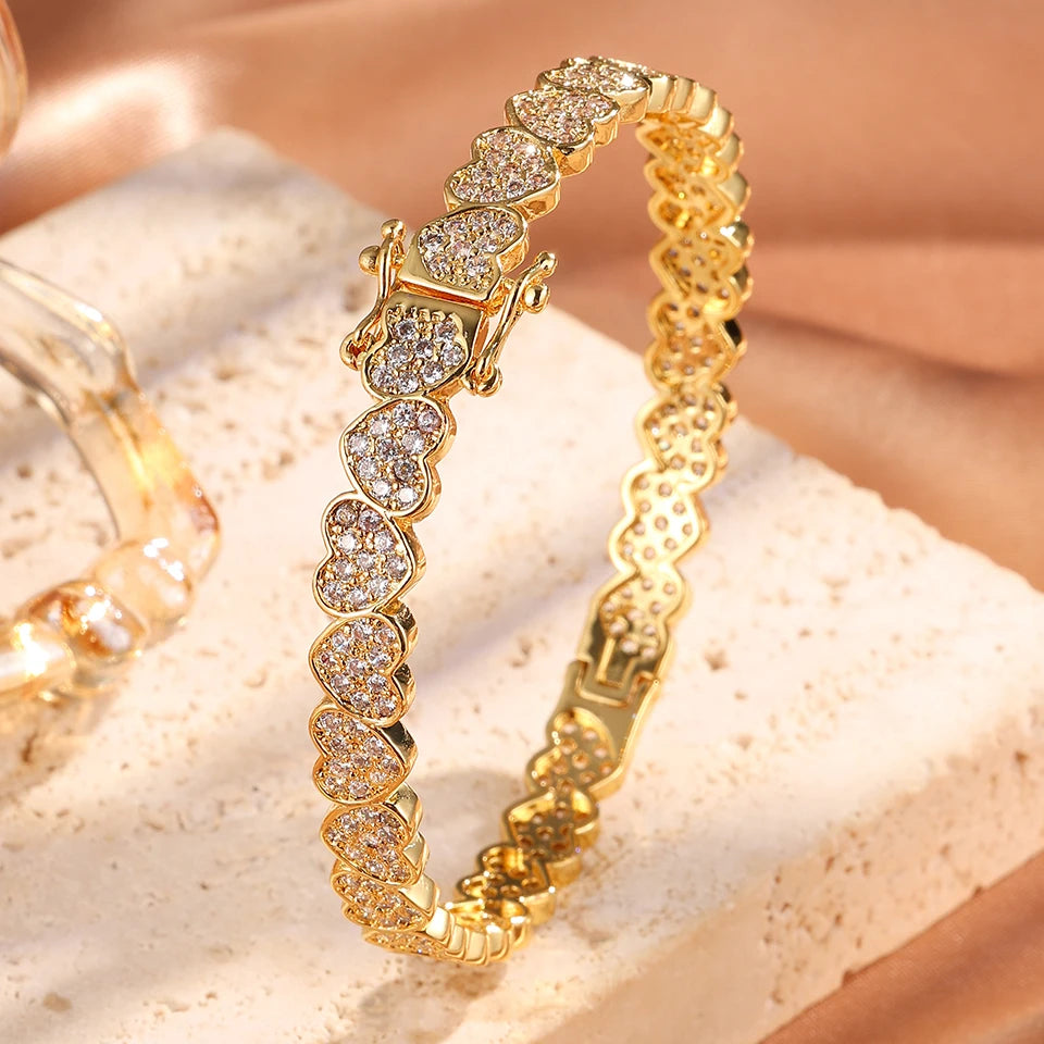 Gold bracelet with heart-shaped diamonds on a beige surface