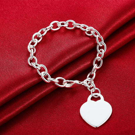 Silver chain bracelet with a heart-shaped tag on red fabric