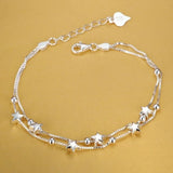 Silver anklet with star-shaped charms on a gold background
