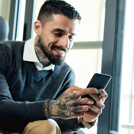 Man with tattoos using a smartphone indoors