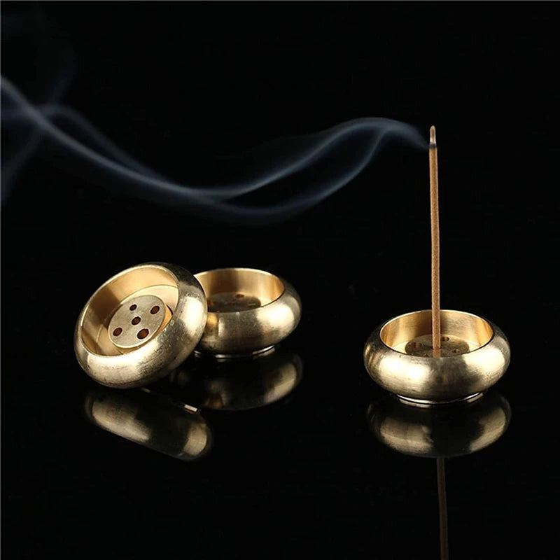 Gold incense burner with a single incense stick on a black background