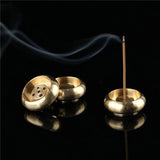 Gold incense burner with a single incense stick on a black background