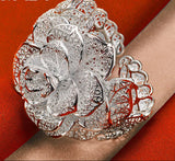 Silver flower-shaped bracelet on a wrist with a red background and 'BABY' branding.
