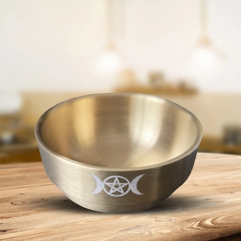 Metallic bowl with a symbol on a wooden surface
