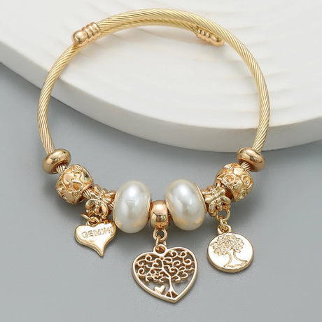 Gold bracelet with various charms on a light gray background
