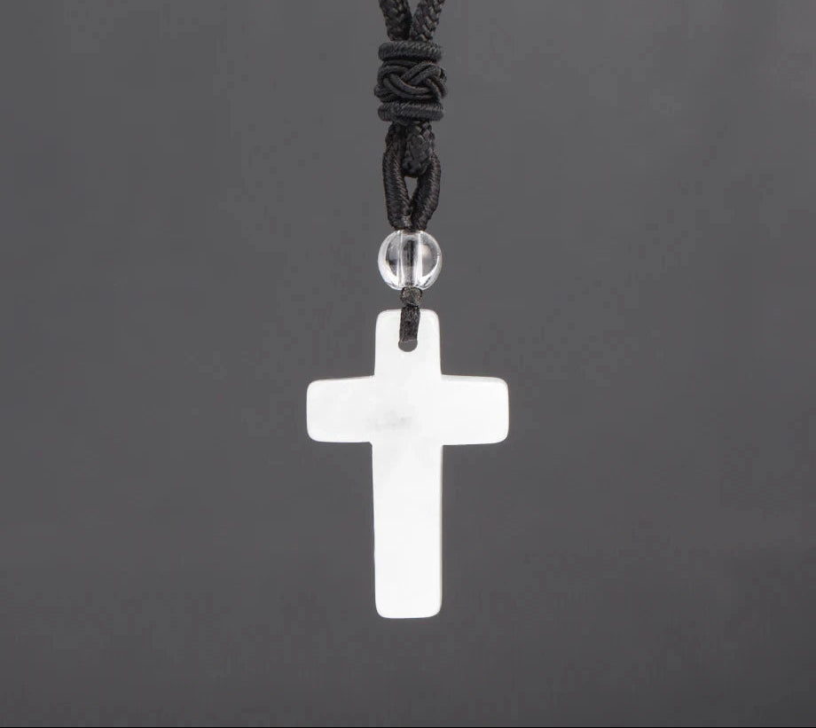 White cross pendant on a black cord against a dark gray background