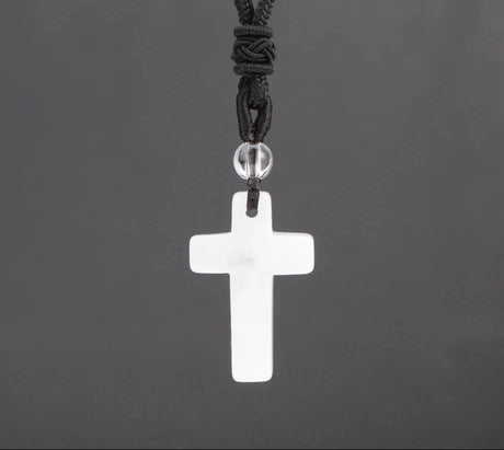 White cross pendant on a black cord against a dark gray background