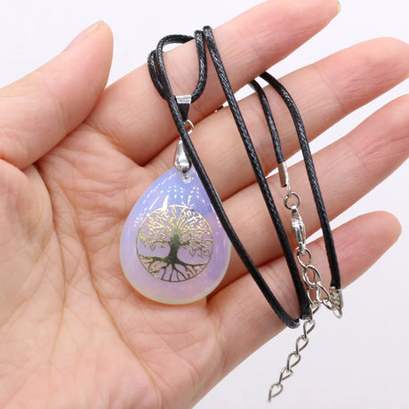 Necklace with a tree of life pendant held in a hand against a white background