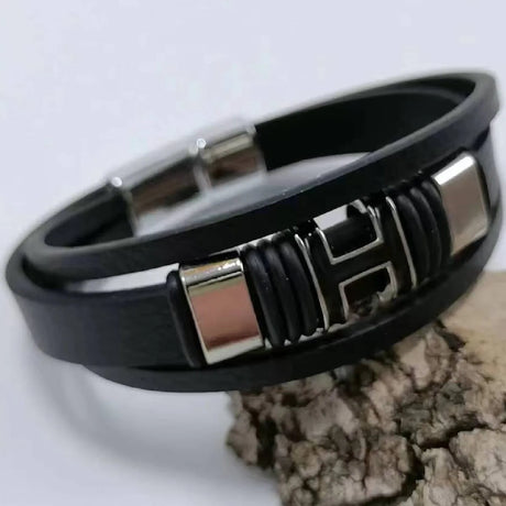 Black leather bracelet with silver accents on a light gray background