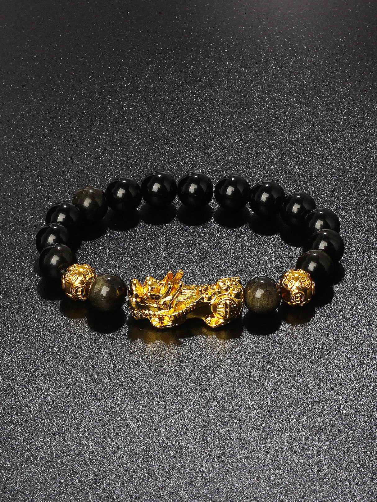 Black beaded bracelet with a gold dragon charm on a dark background
