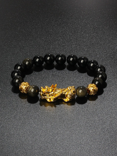 Black beaded bracelet with a gold dragon charm on a dark background