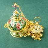 Decorative gold bell with colorful engravings on a green background