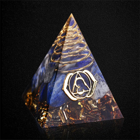 Pyramid-shaped crystal with gold and blue design on a black background