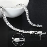 Silver chain bracelet on a dark surface with close-up of clasp showing 'S925' stamp.