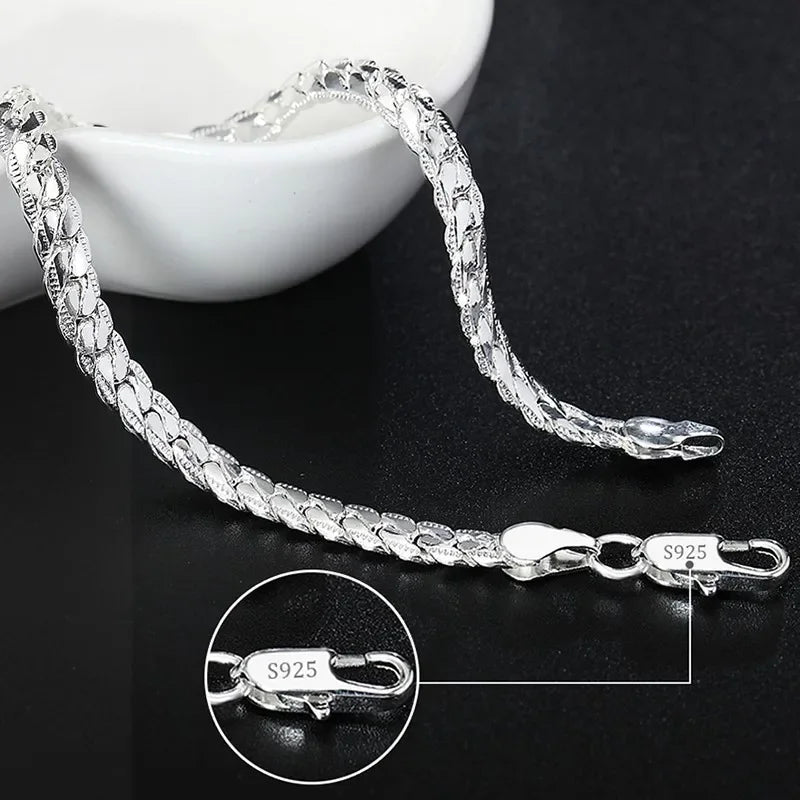 Silver chain bracelet on a dark surface with close-up of clasp showing 'S925' stamp.