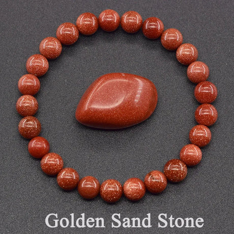 Bracelet made of red stones with a central stone on a gray background, labeled 'Golden Sand Stone'.