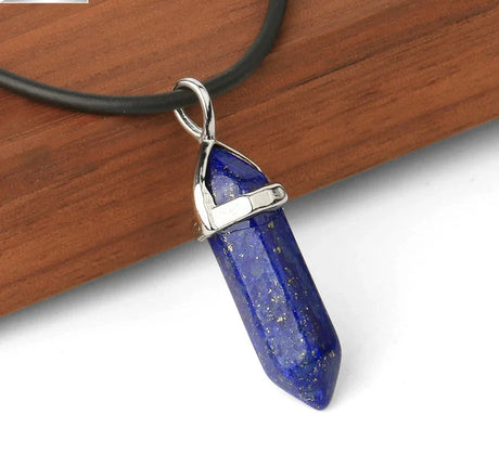 Blue crystal pendant on a black cord with a wooden background