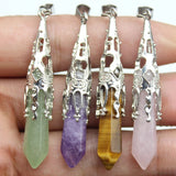 Four crystal pendants in green, purple, yellow, and pink held between fingers.