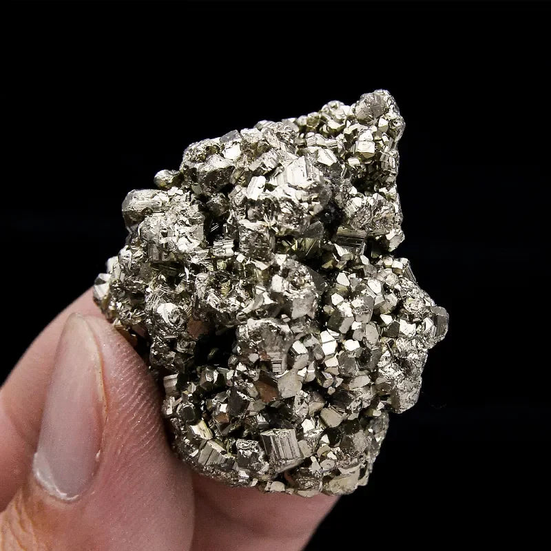 Hand holding a pyrite crystal against a black background
