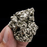 Hand holding a pyrite crystal against a black background