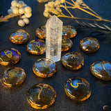 Crystal points and round amber-colored stones with engravings on a dark surface.