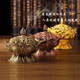 Decorative incense burners in gold, bronze, and copper on a wooden surface with a blurred bookshelf in the background.